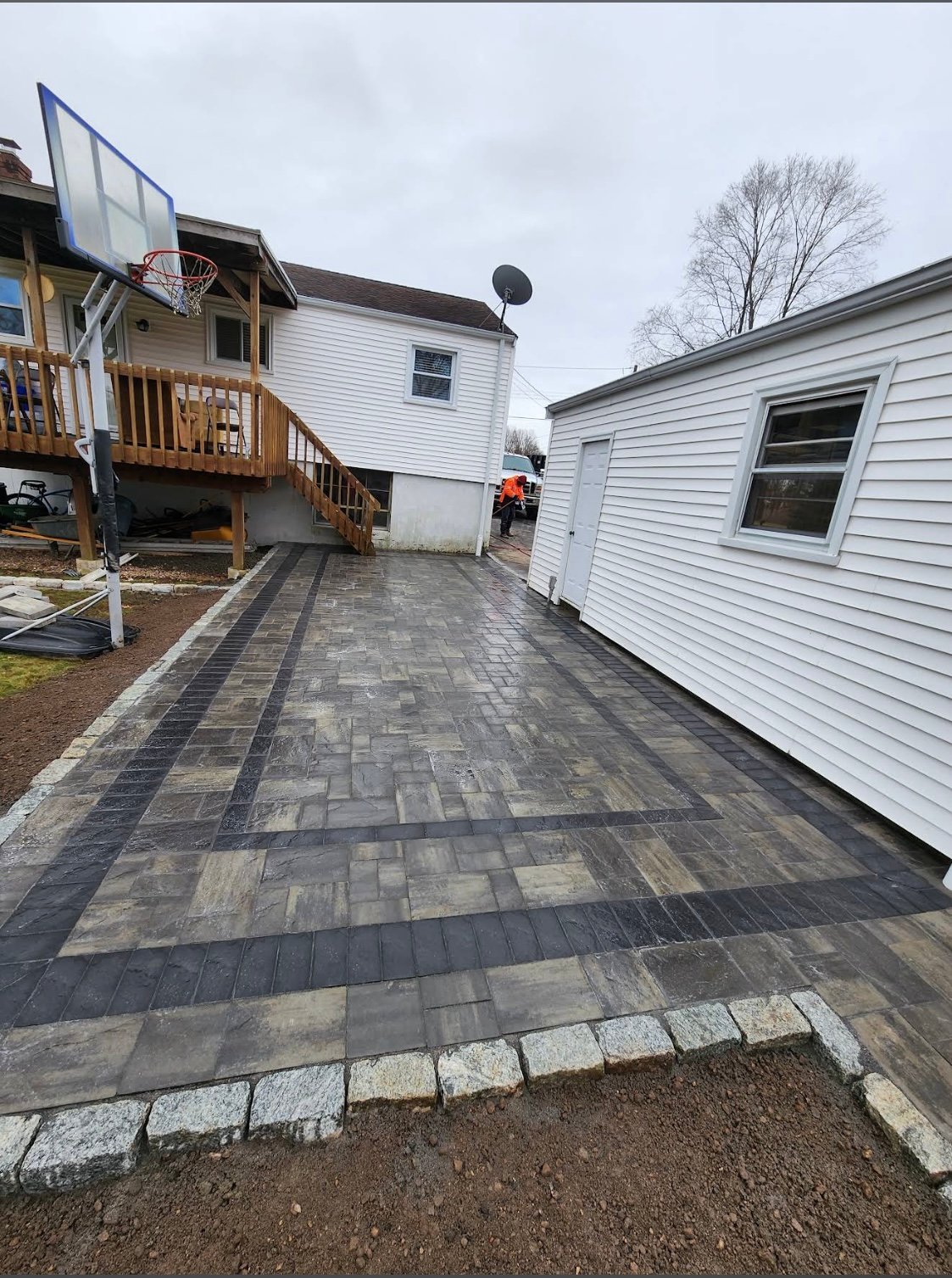 Paved outdoor pathway between two white residential mobile homes with basketball hoop visible on left side