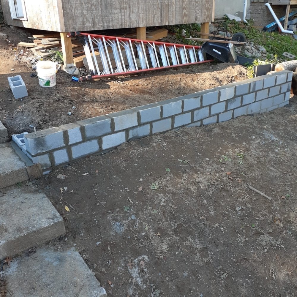 Lorenzo's crew building a block retaining wall on a compacted base at a Connecticut property