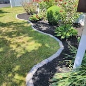 Crisp curved edging separating a manicured lawn from a freshly mulched bed of shrubs and perennials
